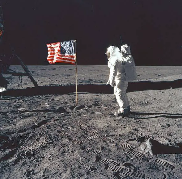 Neil Armstrong plants his flag on the surface of the moon. 