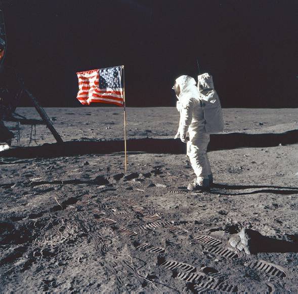 Neil Armstrong plants his flag on the surface of the moon. 