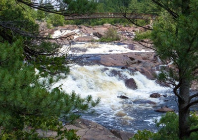 Onaping Falls and bridge seen through pine trees Onaping Ontario
