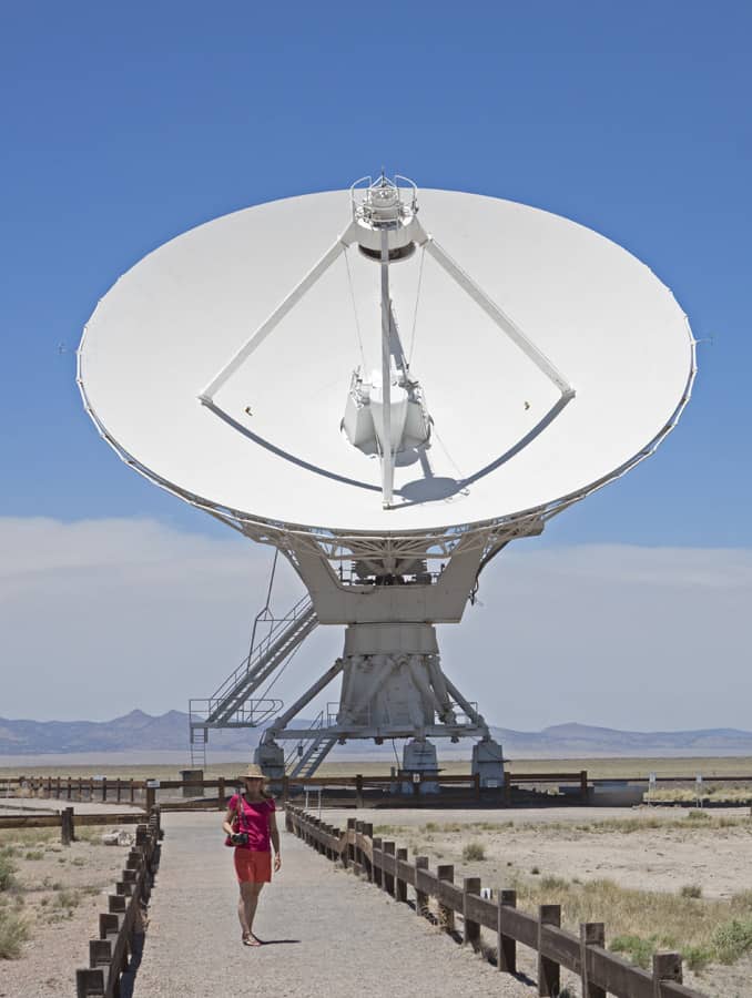 Giant radio telescopes at the VLA move along railroad tracks and turn in unison to follow signals.