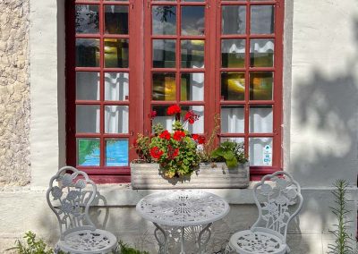 Giverny Village vignette of bistro set in front of red window